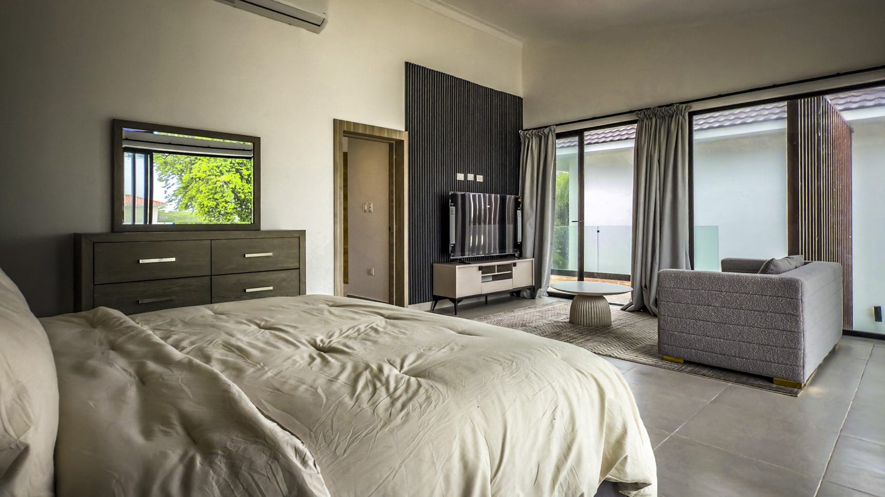 buyDRproperty Luxury villa bedroom with bed, TV, and seating area in Sosua Ocean Village. Sosua Real Estate