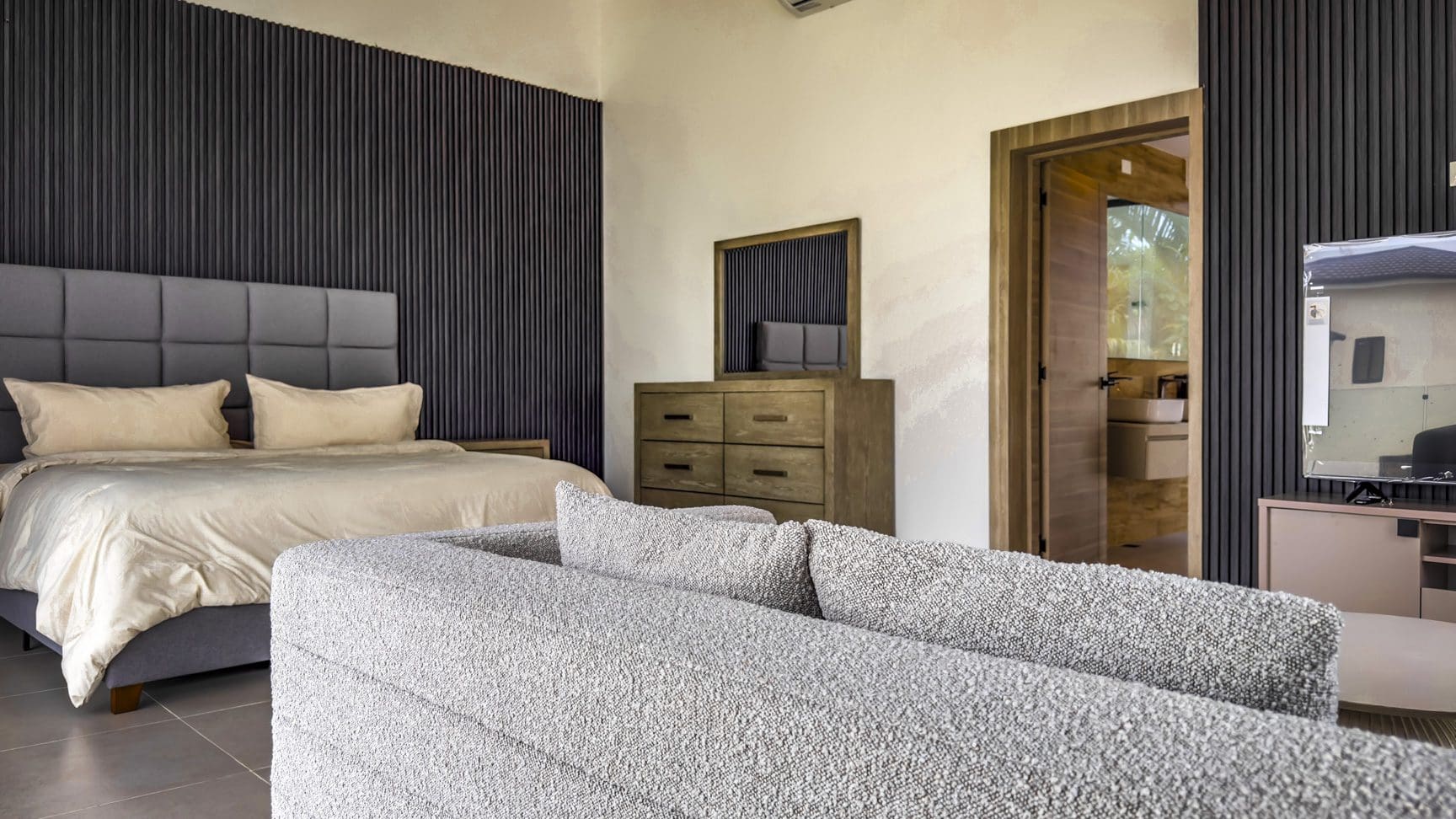 buyDRproperty Luxury villa bedroom with bed, sofa, and dresser. Ocean Village property. Sosua Real Estate