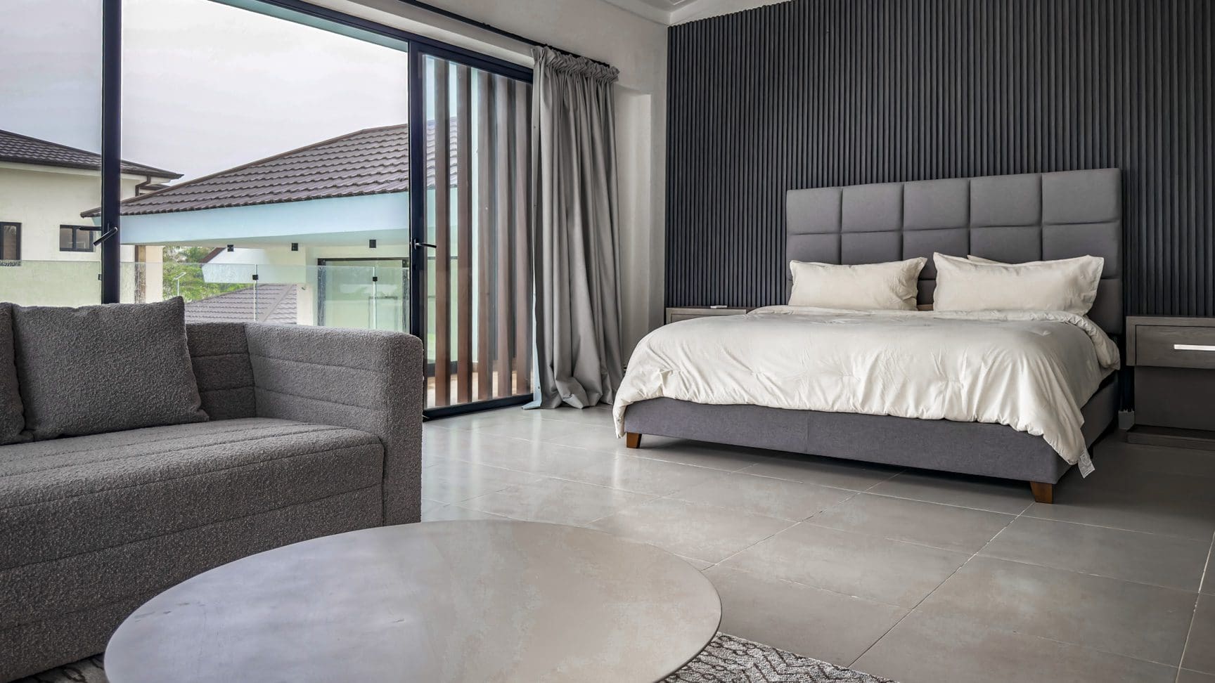 buyDRproperty Luxury bedroom in Sosua Ocean Village villa with gray decor, bed, and view of the villa exterior. Sosua Real Estate
