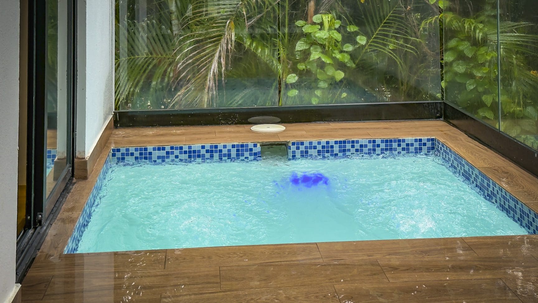 buyDRproperty Indoor plunge pool with blue lighting in a luxury Sosua villa, surrounded by lush greenery. Sosua Real Estate