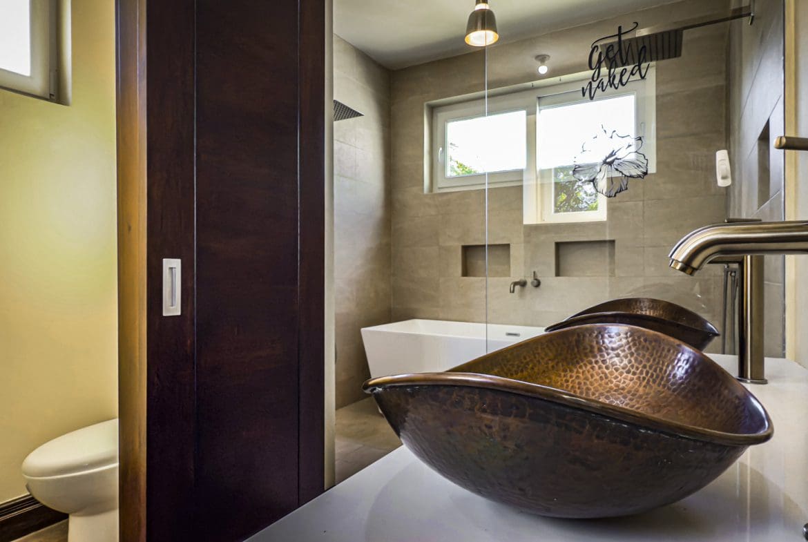 buyDRproperty Modern bathroom featuring a copper sink, glass shower, and a sliding barn door. Sosua Real Estate