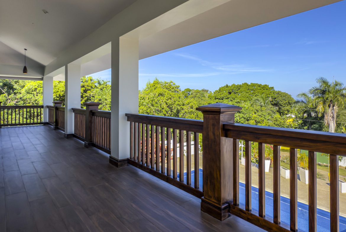 buyDRproperty Balcony view of La Mulata villa with wood railings and lush greenery. For Sale! Sosua Real Estate