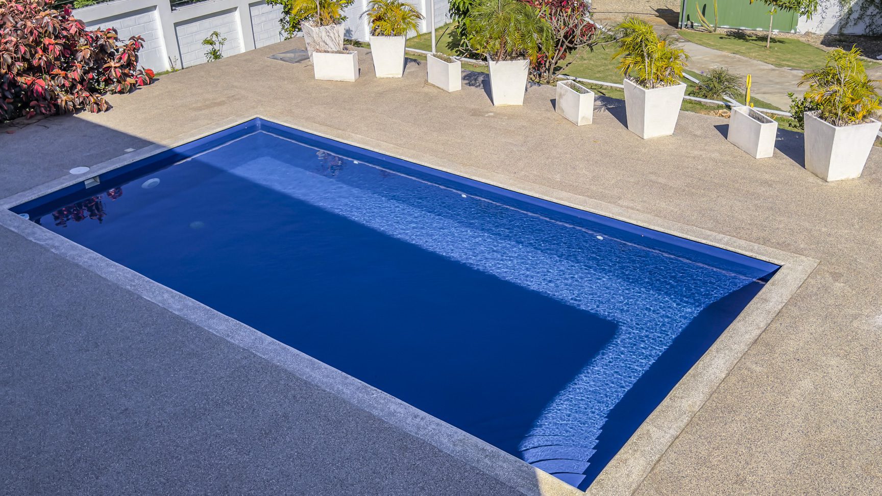 buyDRproperty Swimming pool at a 3 bedroom villa for sale in La Mulata, Dominican Republic. Outdoor view with potted plants. Sosua Real Estate