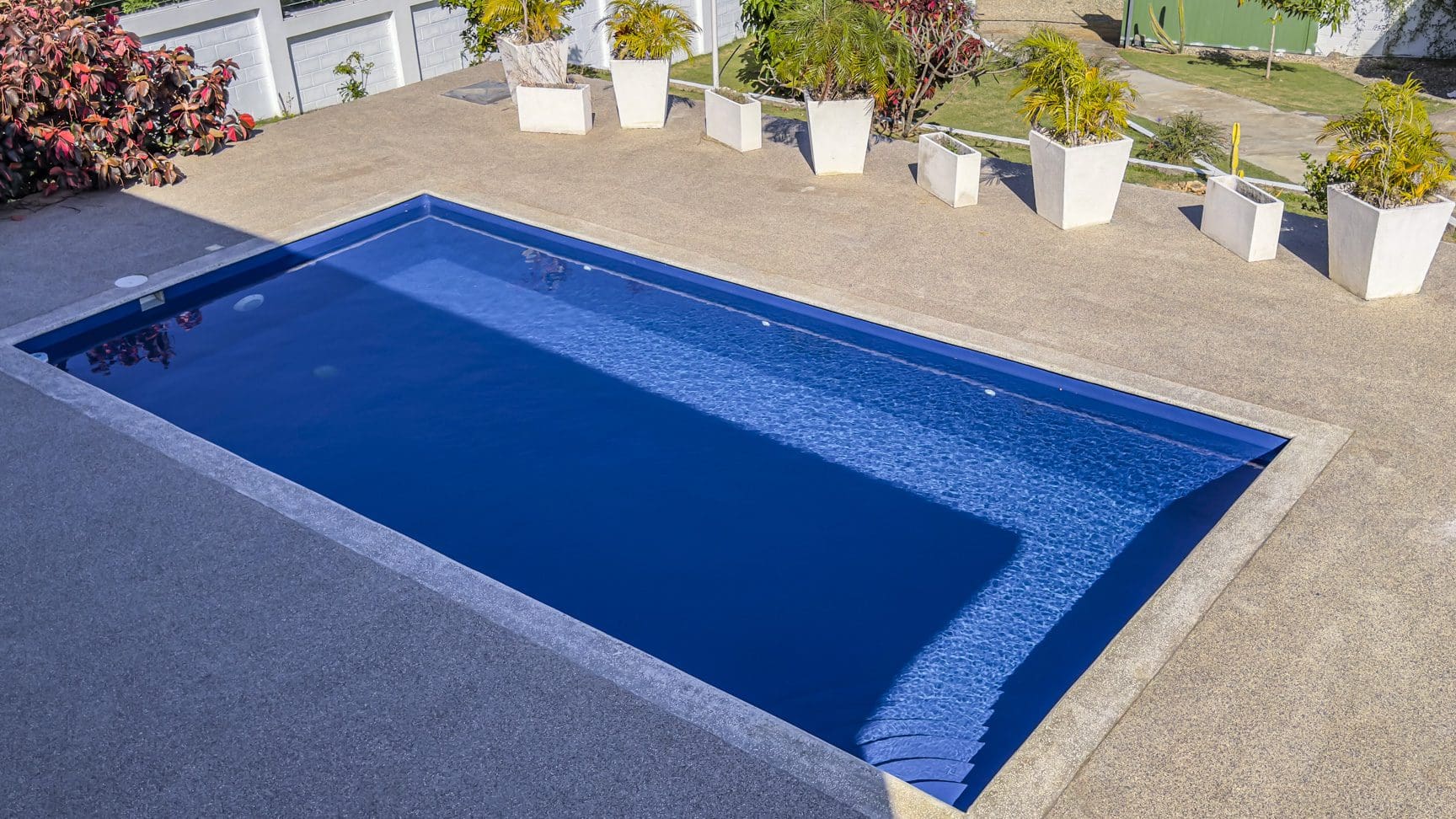 buyDRproperty Swimming pool at a 3 bedroom villa for sale in La Mulata, Dominican Republic. Outdoor view with potted plants. Sosua Real Estate