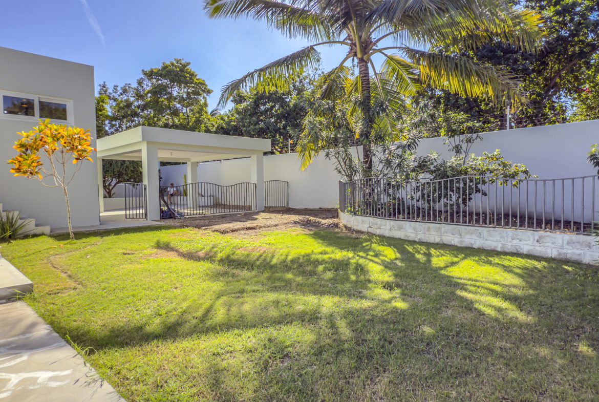 buyDRproperty La Mulata villa for sale: Backyard with lawn, patio, and tropical landscaping. Sosua Real Estate