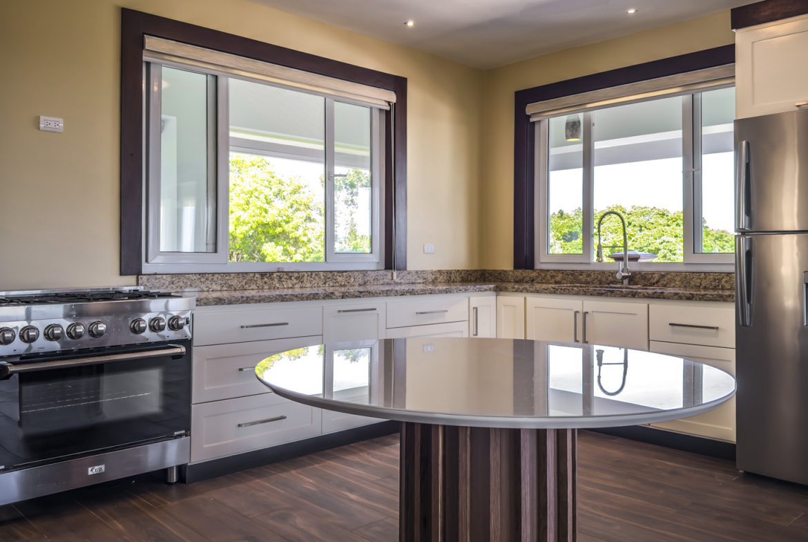 buyDRproperty Modern kitchen with stainless steel appliances and large windows in La Mulata villa. Sosua Real Estate