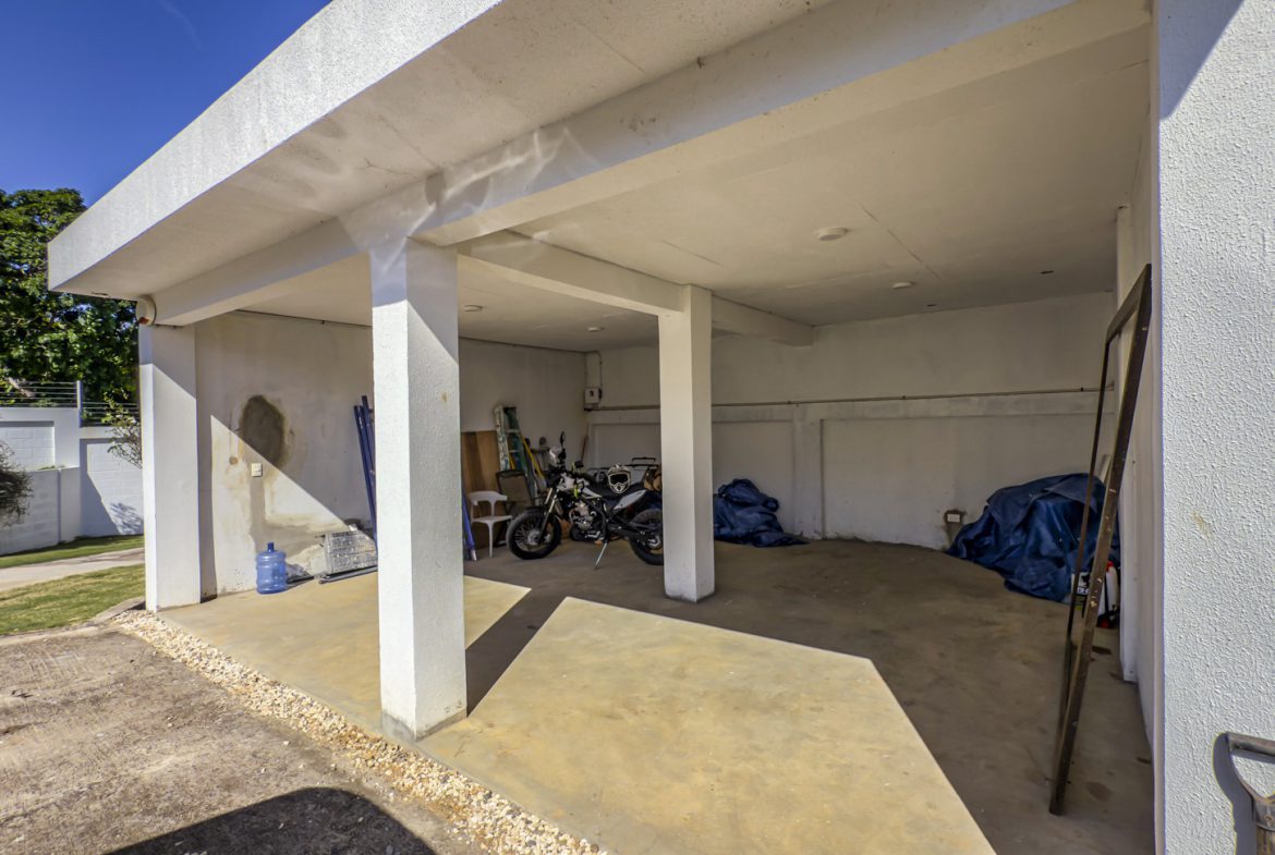 buyDRproperty Open carport with motorcycle, tools, and blue tarps in La Mulata villa. Sosua Real Estate