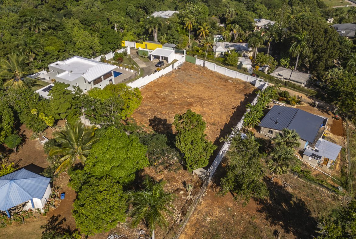buyDRproperty Aerial view of a 3-bedroom villa for sale in La Mulata, Dominican Republic, surrounded by lush greenery and neighboring homes. Sosua Real Estate