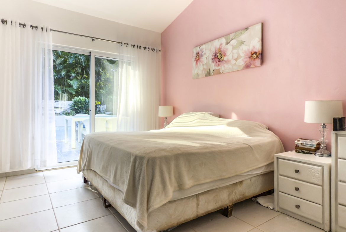 buyDRproperty Bedroom in a villa with pink walls, white tile floor, and sliding glass doors to a garden. Sosua Real Estate