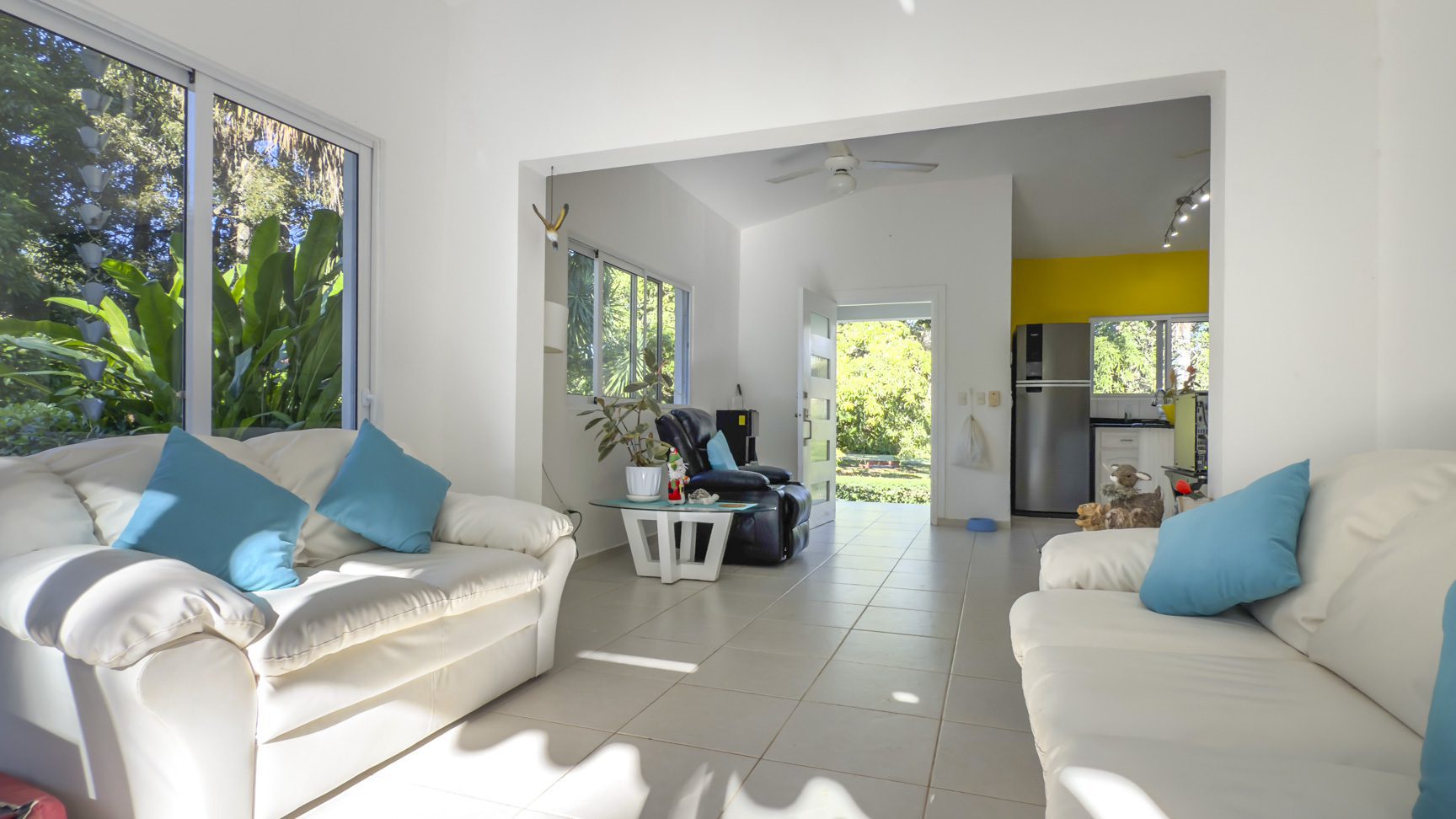 buyDRproperty Bright living space in a villa with white sofas and tile floors, leading to a garden view. Sosua Real Estate