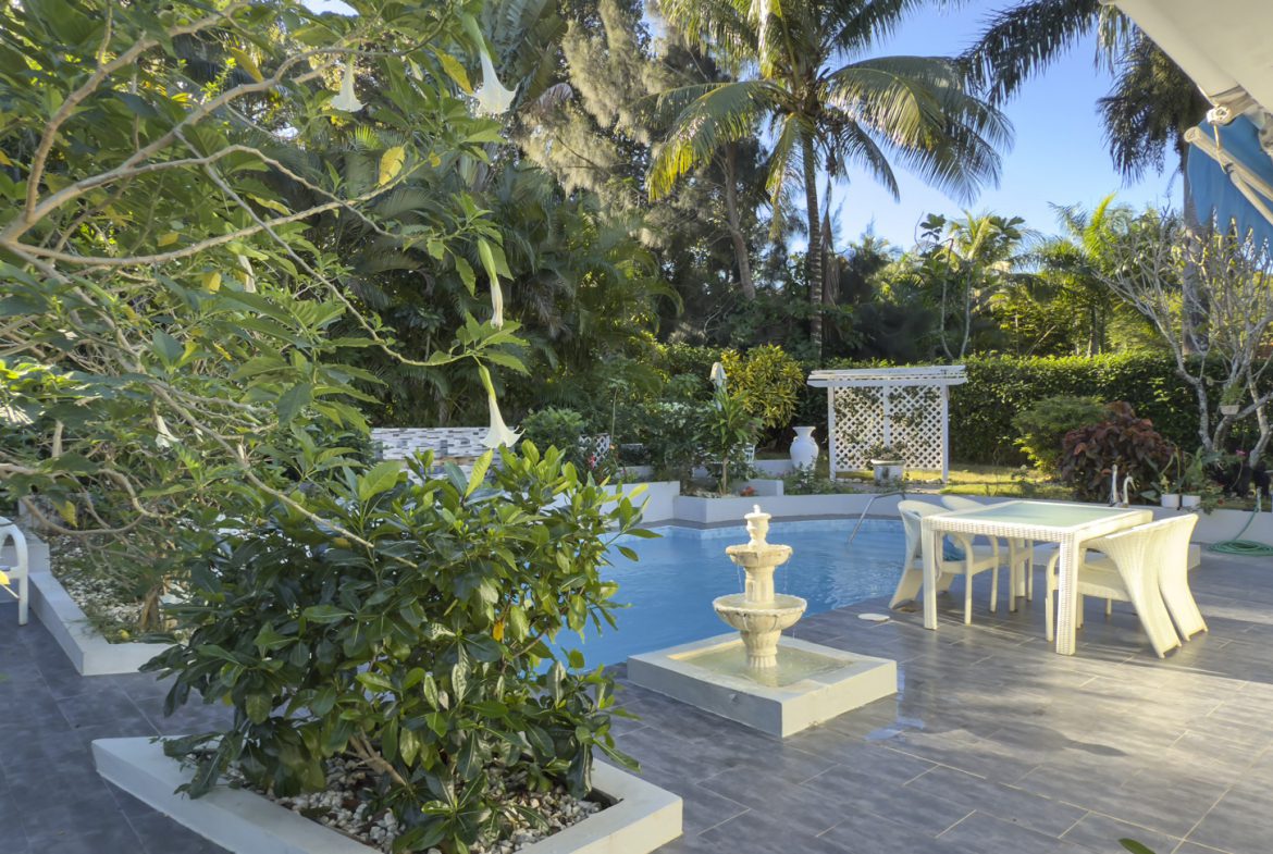 buyDRproperty Colibri villa backyard with pool, fountain, patio furniture, and tropical garden. Sosua Real Estate