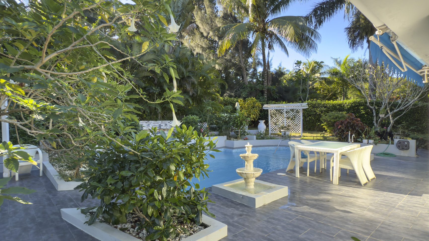 buyDRproperty Colibri villa backyard with pool, fountain, patio furniture, and tropical garden. Sosua Real Estate