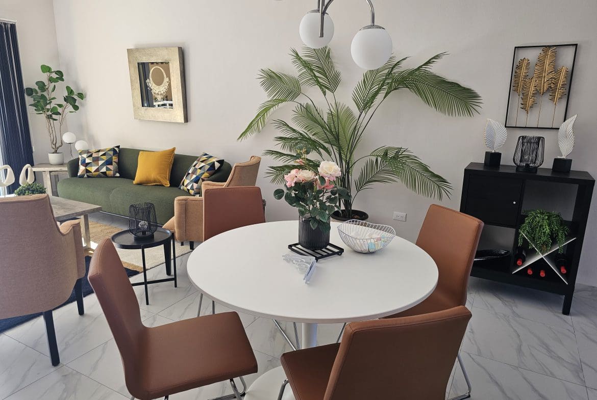 buyDRproperty Modern living room with green sofa, round white dining table, and brown chairs. Interior design. Sosua Real Estate