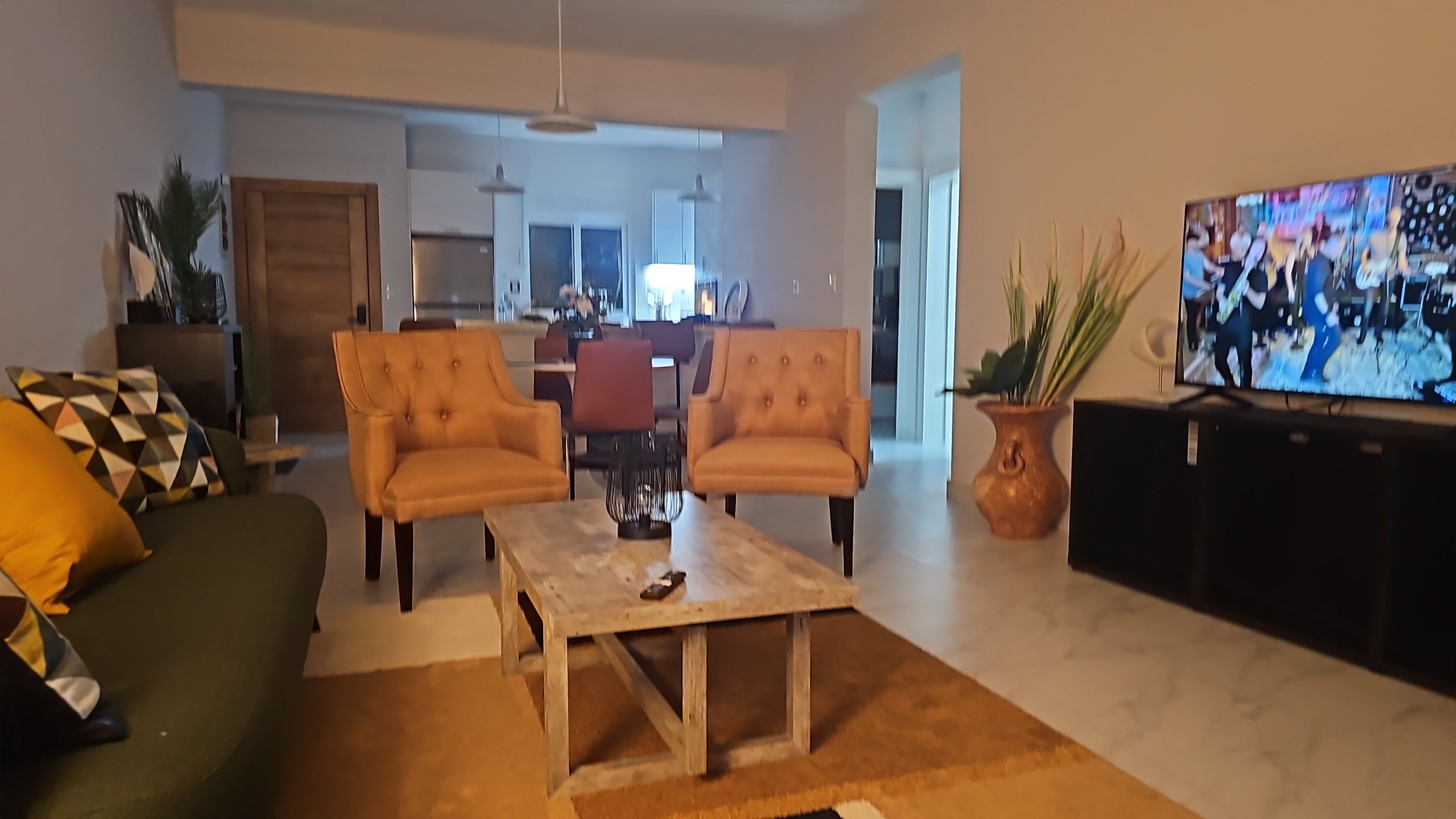 buyDRproperty Cozy living room with tan armchairs, olive green sofa, and TV. Open floor plan home interior. Sosua Real Estate