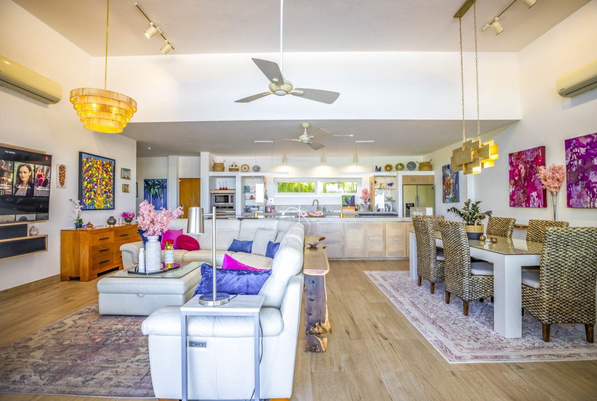 buyDRproperty Bright, open-concept living space with modern furniture, a kitchen, and a dining area under a high ceiling. Sosua Real Estate