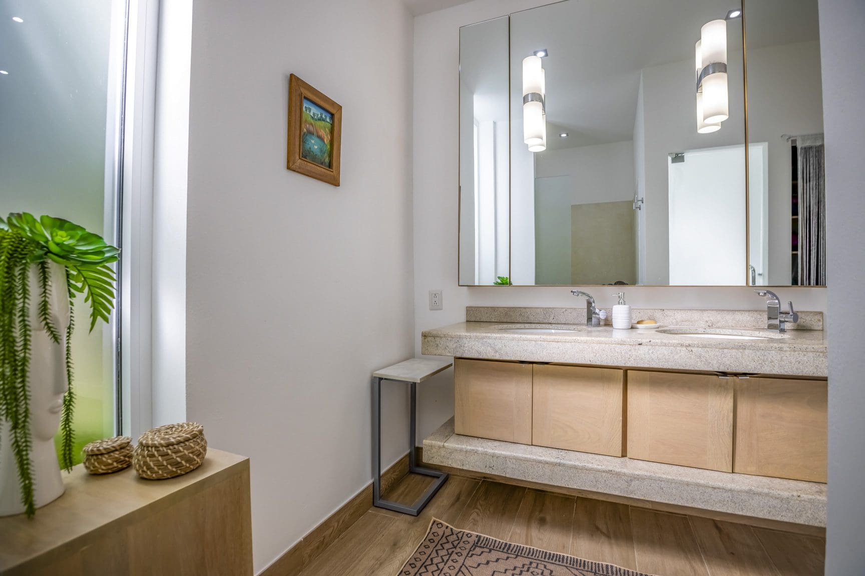 buyDRproperty Modern bathroom with double vanity, light wood cabinets, stone countertop, and decorative accents. Sosua Real Estate