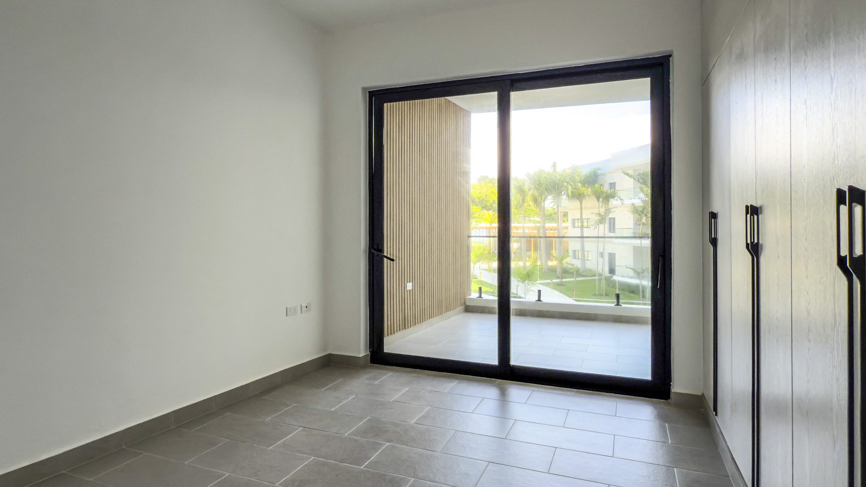 buyDRproperty Bright, modern room with sliding glass doors to a balcony and built-in wardrobe. Sosua Real Estate