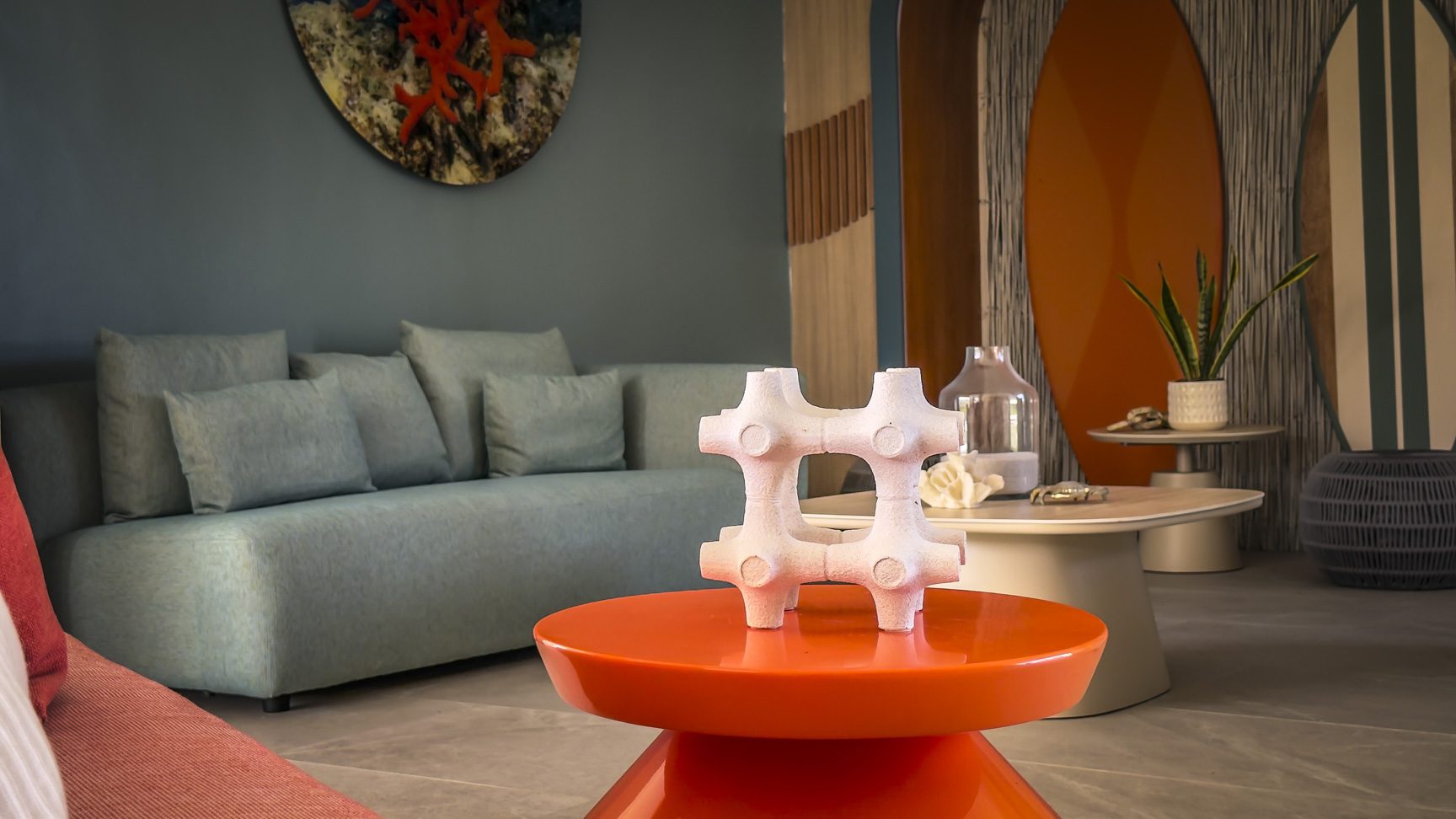 buyDRproperty Modern living room with blue sofa, orange table, and surfboard decor. Coastal interior design. Sosua Real Estate