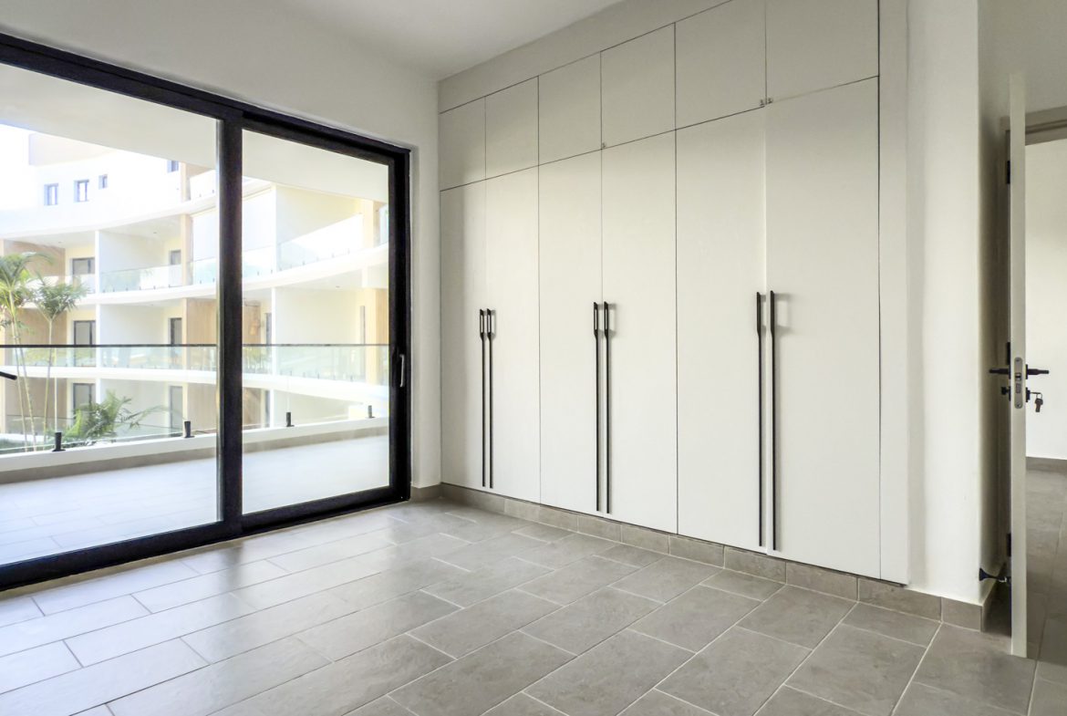 buyDRproperty Bright room with sliding glass door, built-in white wardrobe, and gray tile floor. Sosua Real Estate