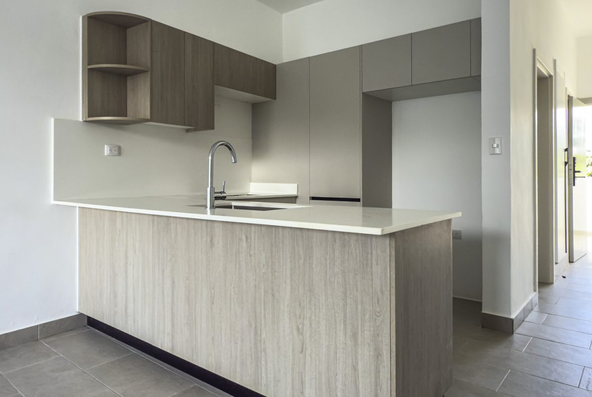 buyDRproperty Modern kitchen with light wood cabinets, white countertops, and tile flooring. Minimalist design. Sosua Real Estate