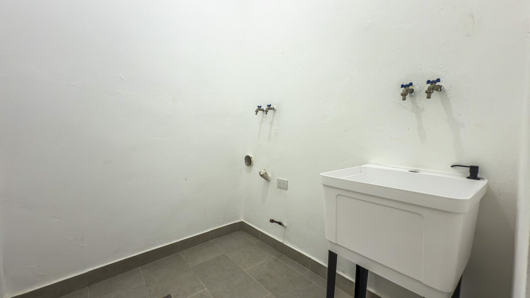 buyDRproperty Laundry room with a utility sink, faucet fixtures, and gray tile floor. Sosua Real Estate