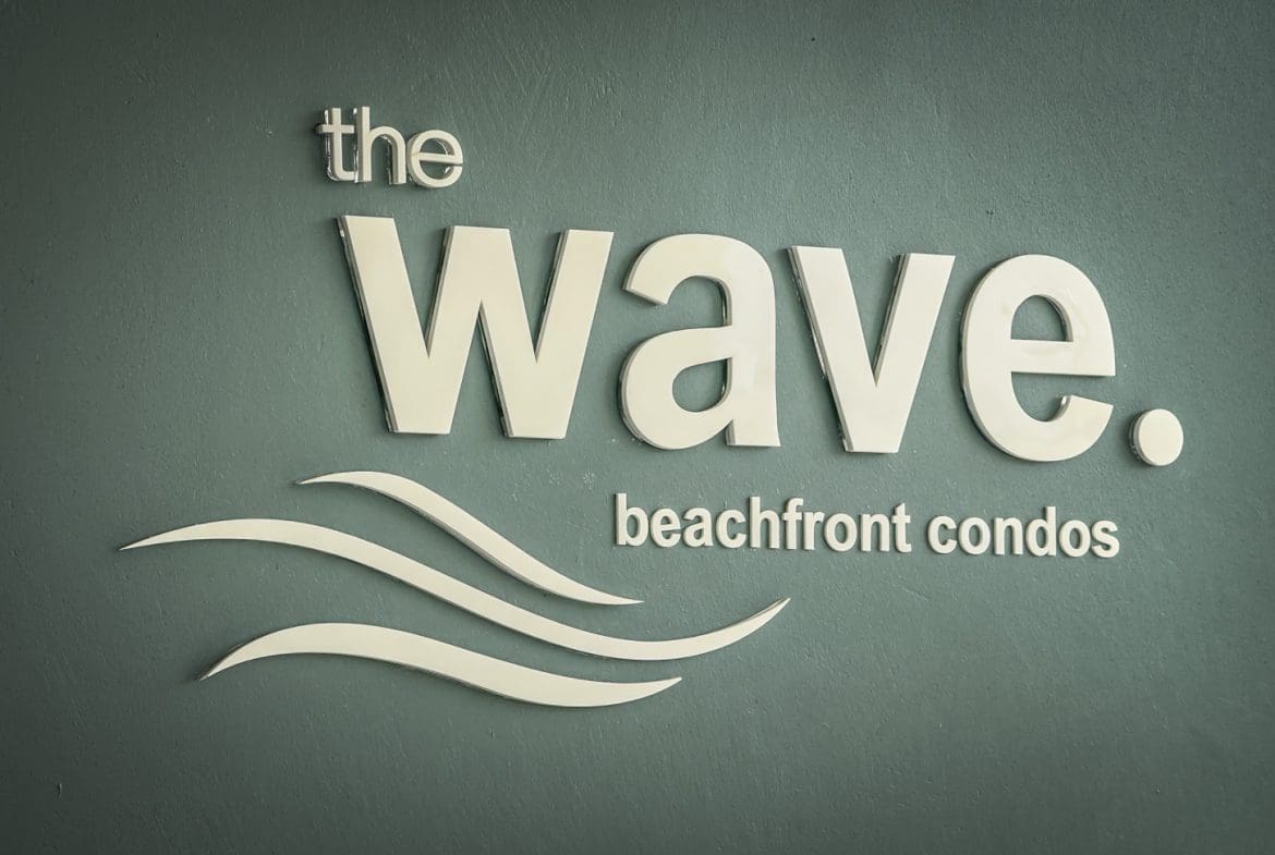 buyDRproperty The Wave beachfront condos sign with wave graphic. Sosua Real Estate