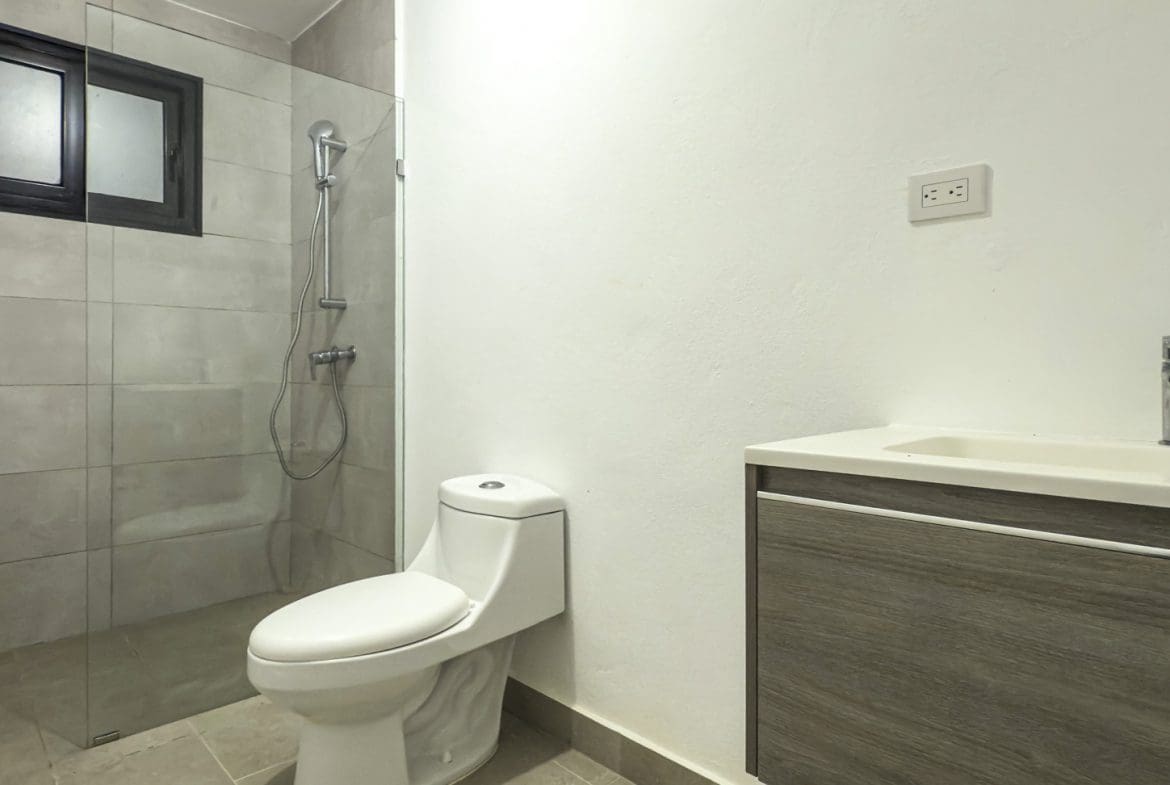 buyDRproperty Modern bathroom with walk-in shower, toilet, and vanity with sink. Clean, contemporary design. Sosua Real Estate