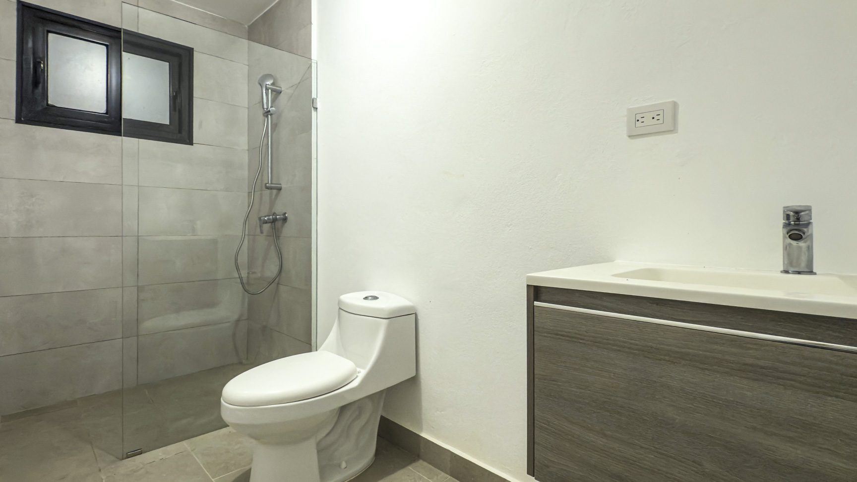 buyDRproperty Modern bathroom with walk-in shower, toilet, and vanity with sink. Clean, contemporary design. Sosua Real Estate