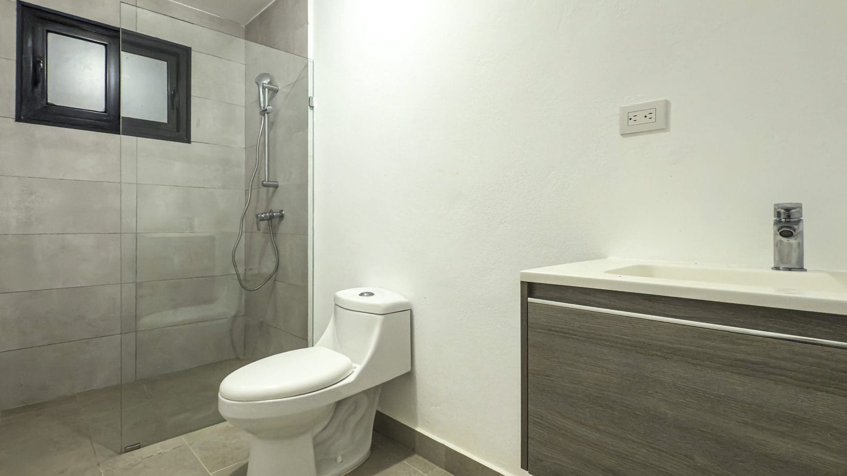 buyDRproperty Modern bathroom with walk-in shower, toilet, and vanity with sink. Clean, contemporary design. Sosua Real Estate