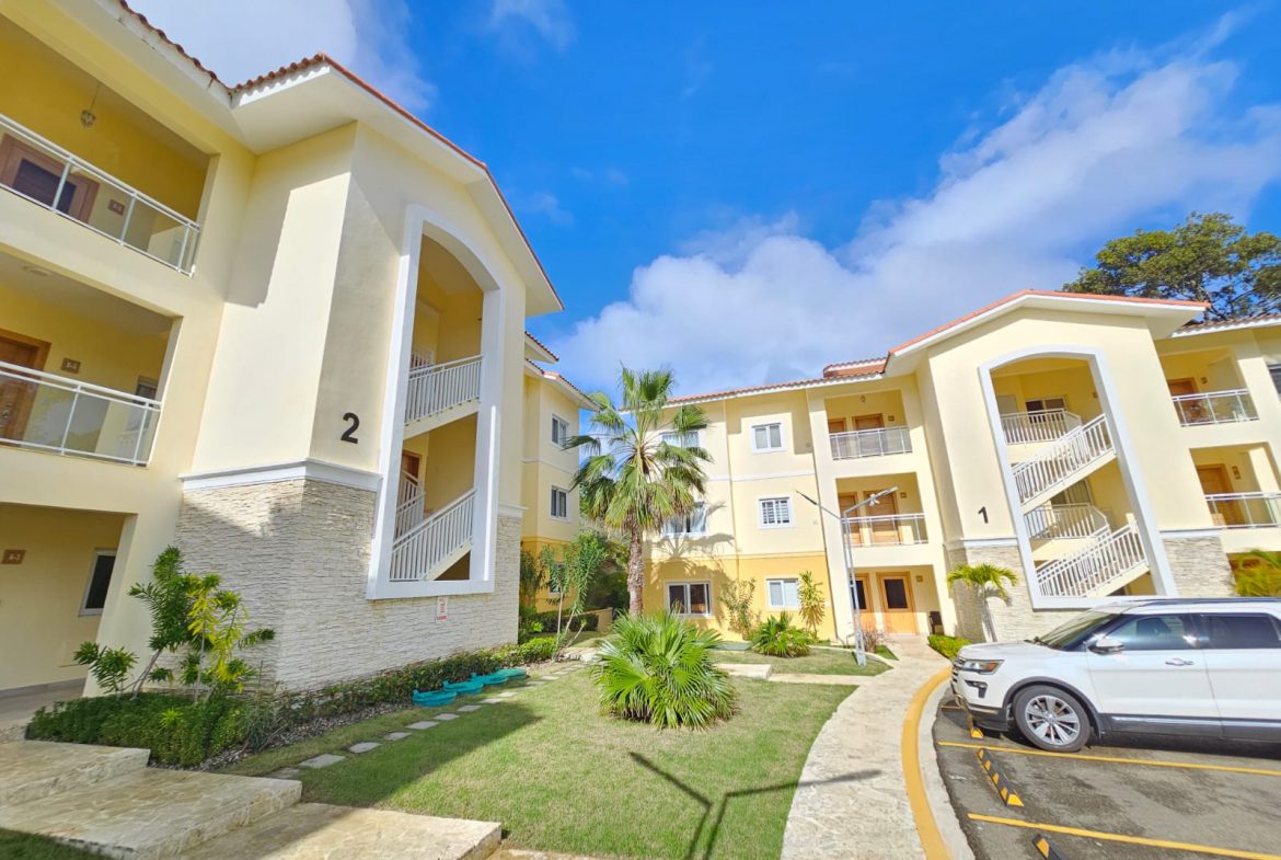 buyDRproperty Exterior of sunny yellow condos with balconies and a well-maintained lawn. Sosua Real Estate