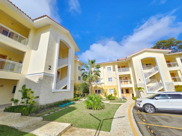 buyDRproperty Exterior of sunny yellow condos with balconies and a well-maintained lawn. Sosua Real Estate