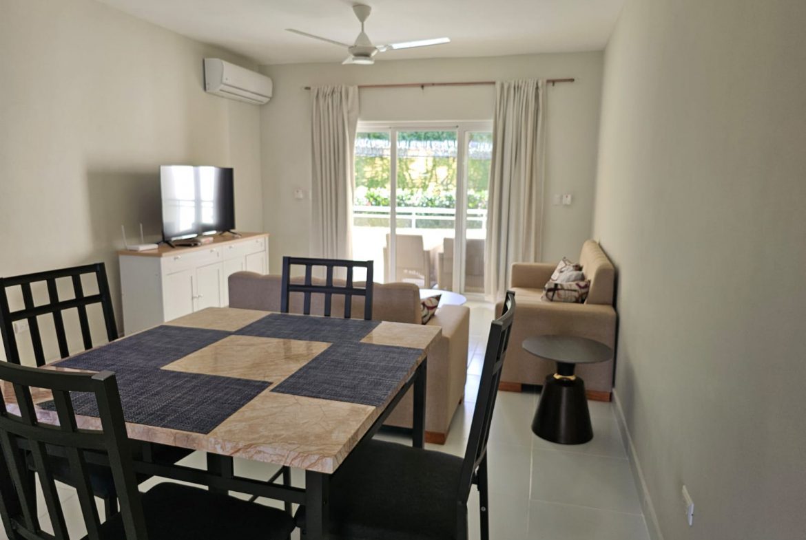 buyDRproperty Bright living room with dining table, sofa, and balcony access. Sosua Real Estate