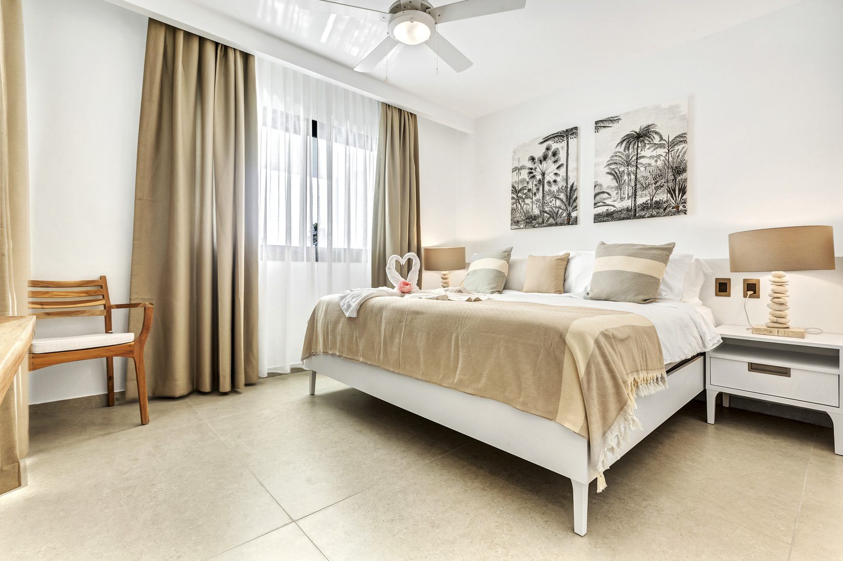 buyDRproperty Bright bedroom with white bed, beige accents, and tropical artwork above the headboard. Sosua Real Estate
