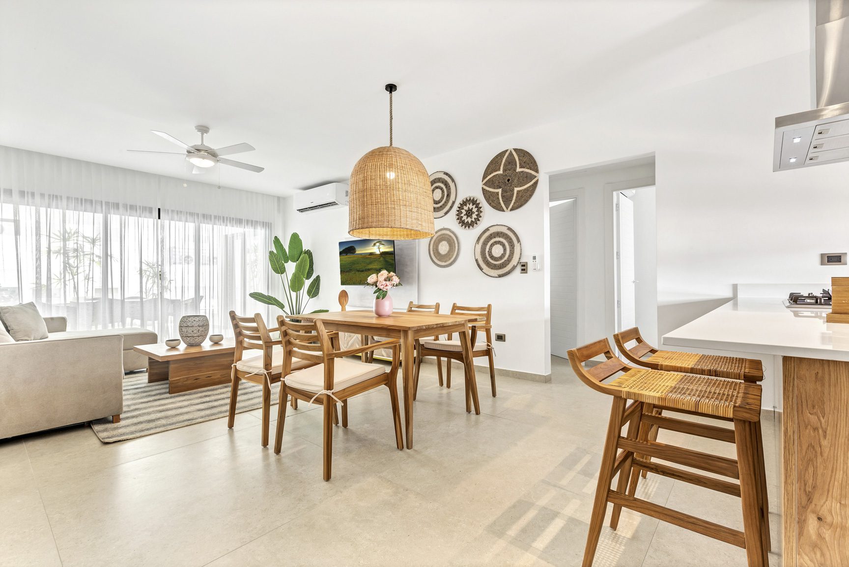 buyDRproperty Modern open-plan dining area with wooden table, rattan chairs, and living room sofa Sosua Real Estate