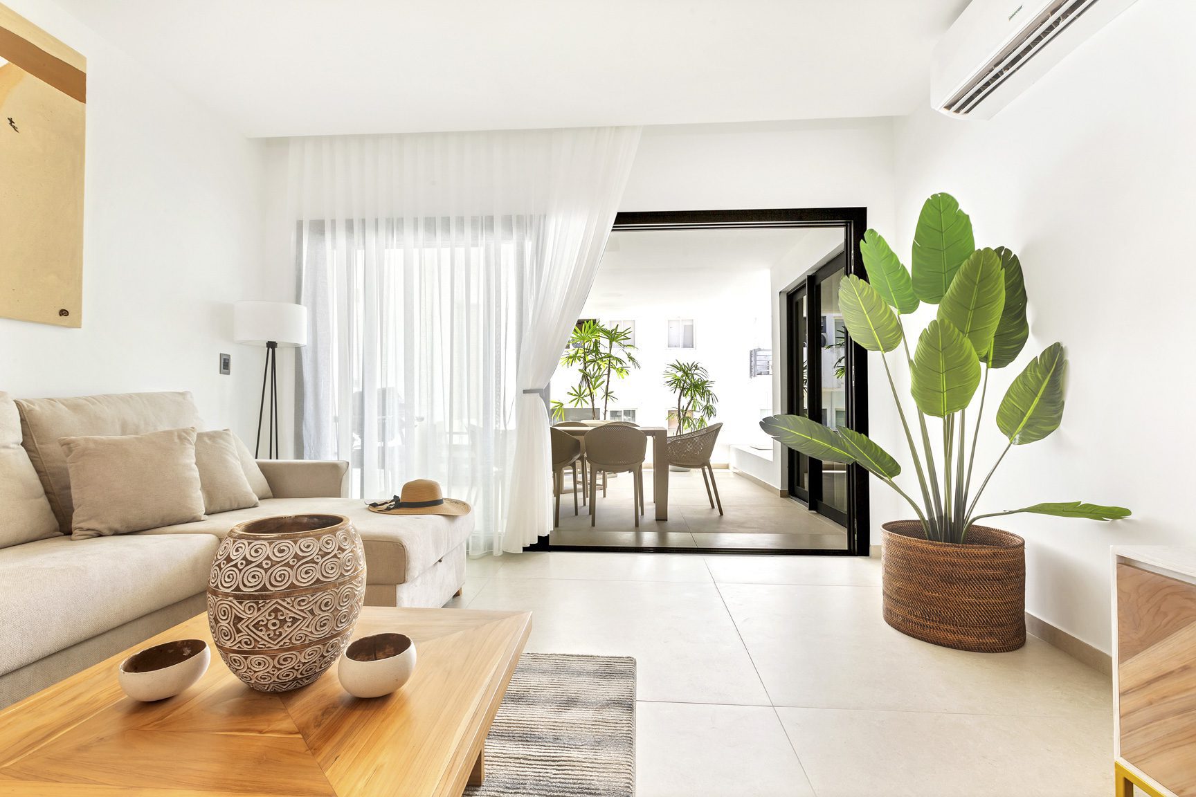 buyDRproperty Bright living room with sofa, plant, and patio view. Sosua Real Estate