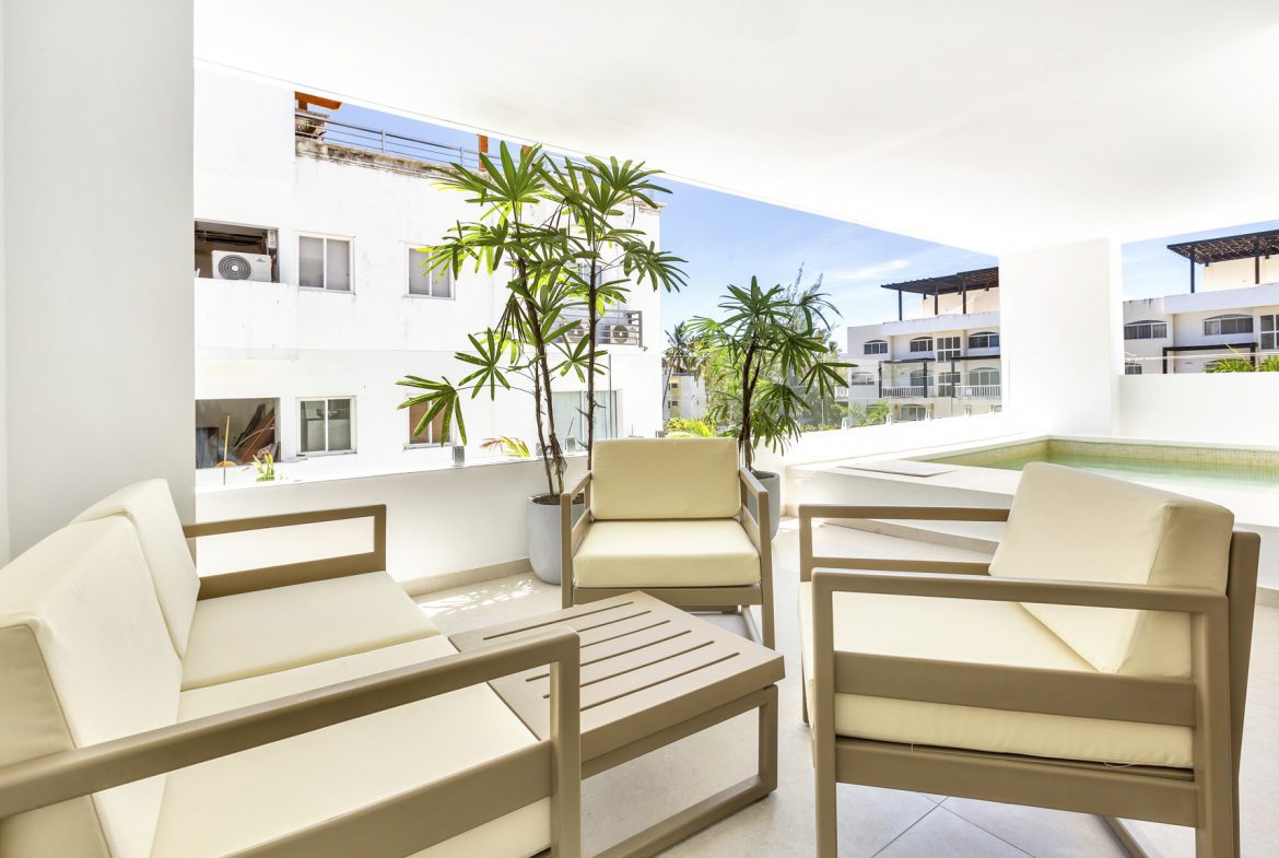 buyDRproperty Modern outdoor patio with beige furniture, tropical plants, and pool Sosua Real Estate