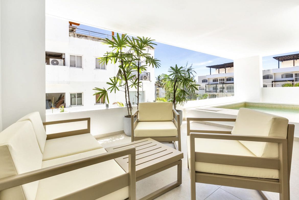 buyDRproperty Modern outdoor patio with beige furniture, tropical plants, and pool Sosua Real Estate