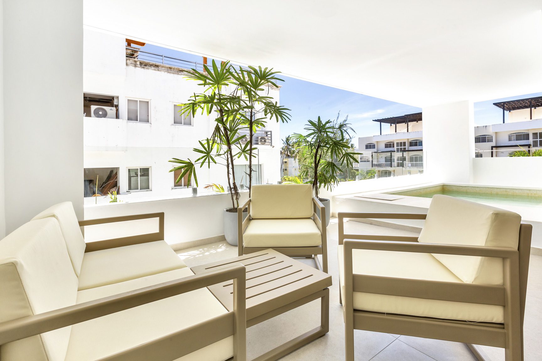 buyDRproperty Modern outdoor patio with beige furniture, tropical plants, and pool Sosua Real Estate