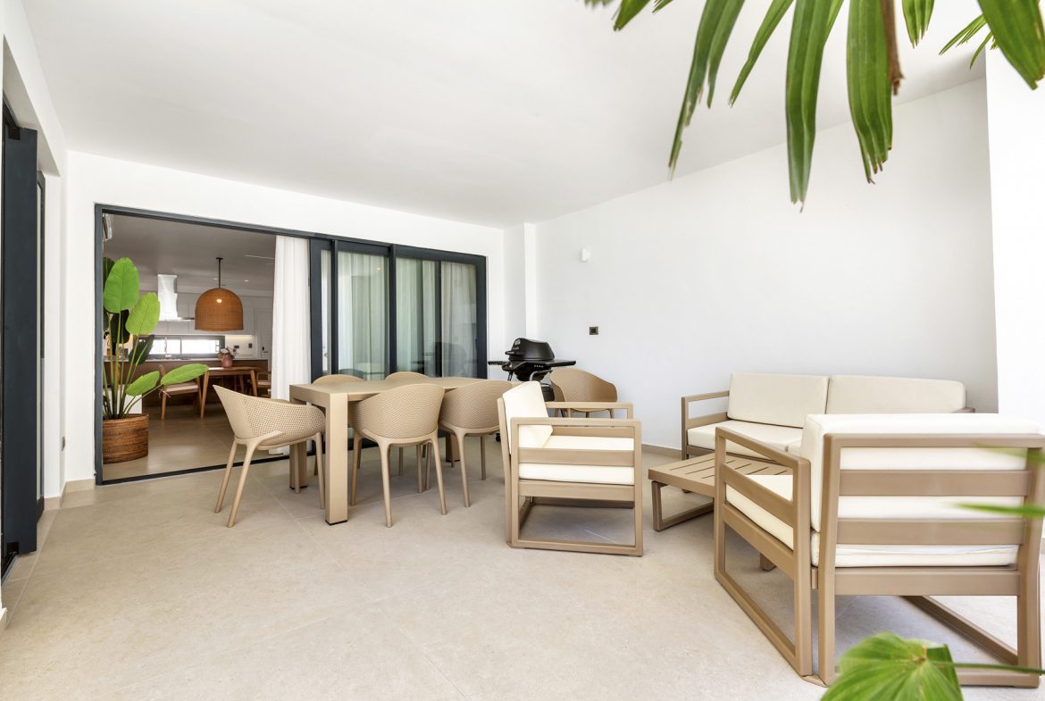 buyDRproperty Outdoor patio with dining table, chairs, sofa, and grill, leading to a modern kitchen. Sosua Real Estate