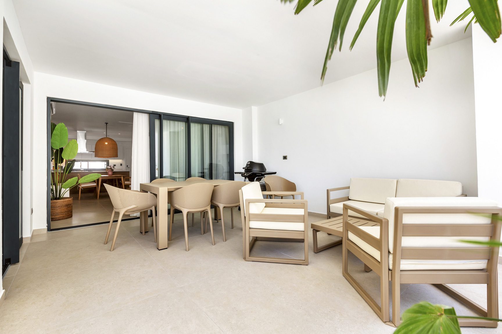 buyDRproperty Outdoor patio with dining table, chairs, sofa, and grill, leading to a modern kitchen. Sosua Real Estate