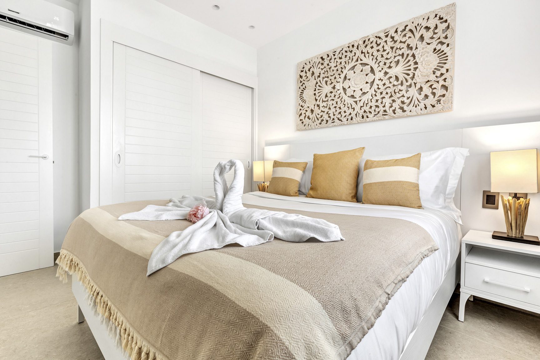 buyDRproperty Luxurious bedroom with swan towel art, gold cushions, and carved wooden headboard. Sosua Real Estate
