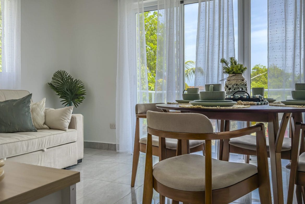 buyDRproperty Bright living room with dining table set for a meal, sofa, and balcony view. Sosua Real Estate