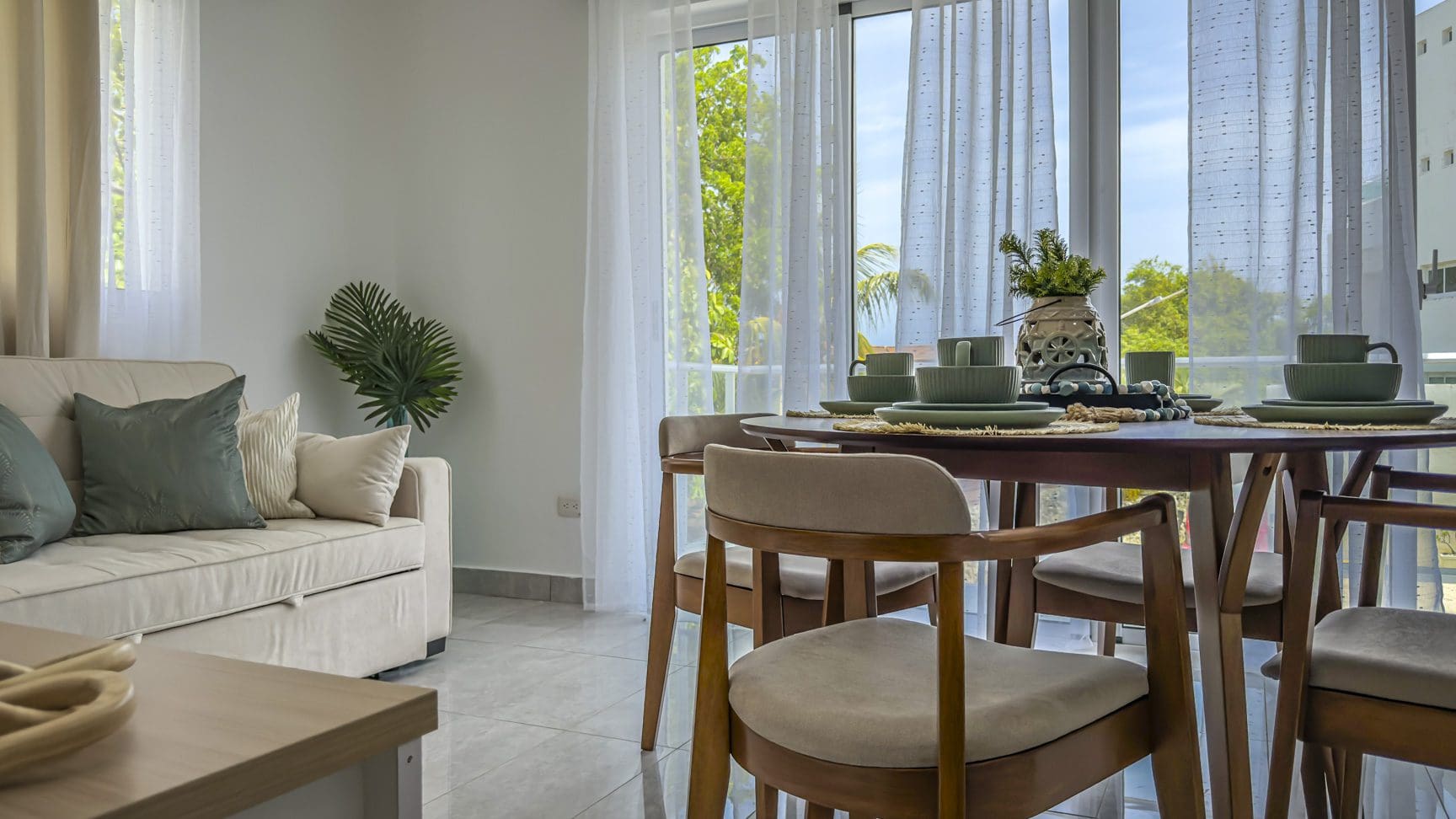 buyDRproperty Bright living room with dining table set for a meal, sofa, and balcony view. Sosua Real Estate