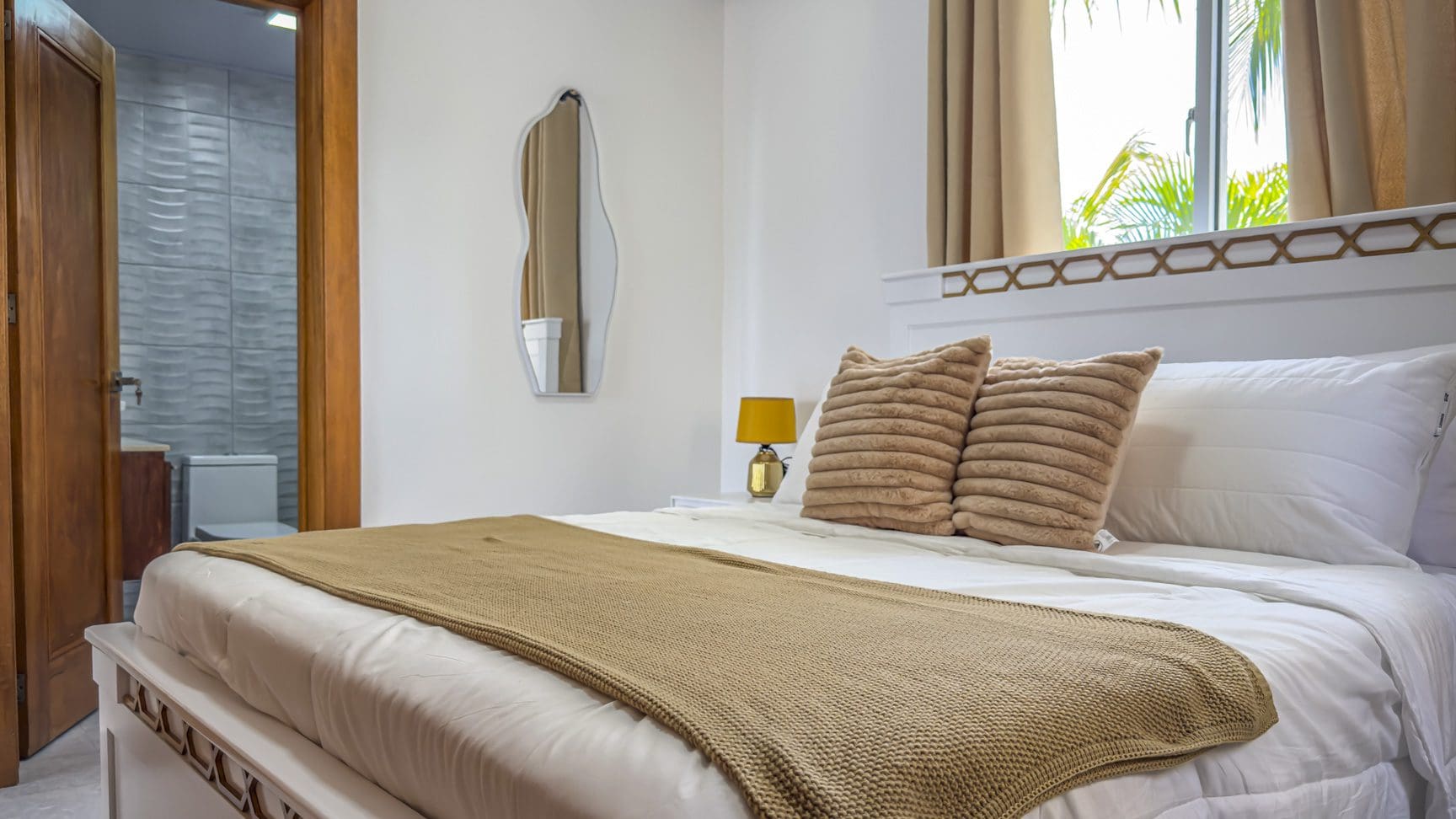 buyDRproperty Bright bedroom with white bedding, neutral accents, and bathroom access. Sosua Real Estate
