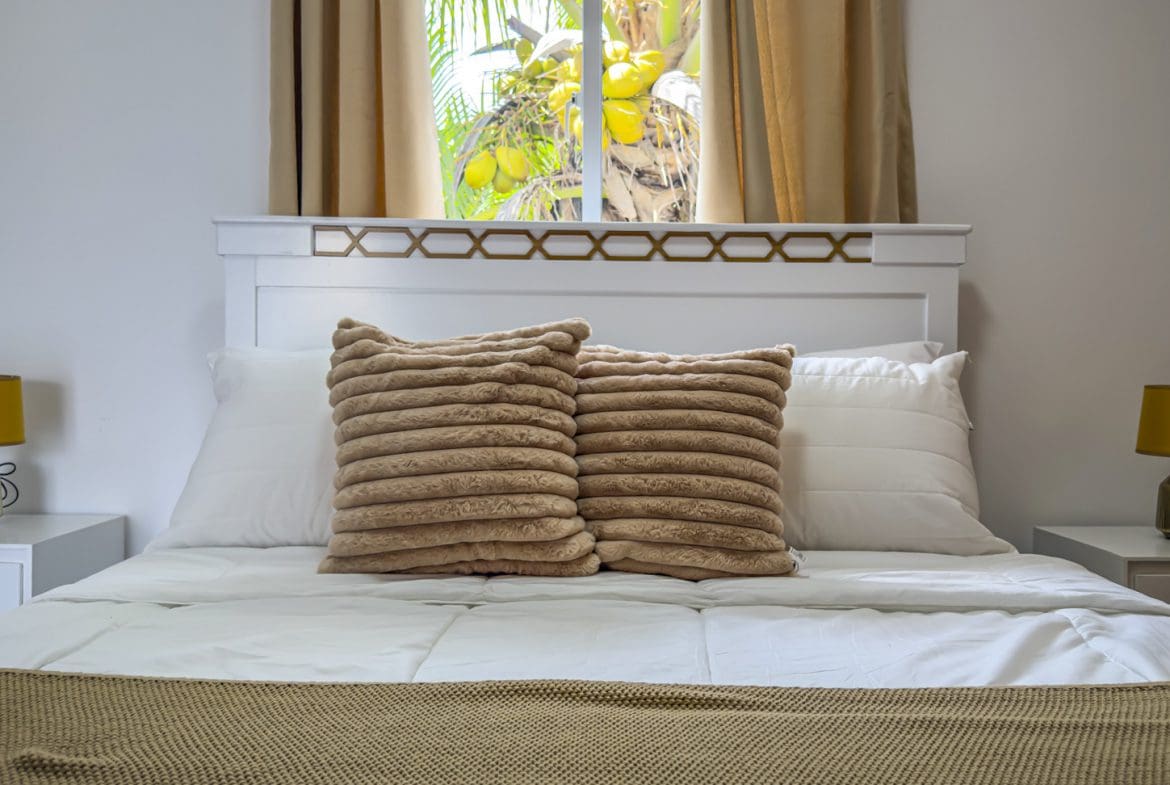 buyDRproperty Bedroom with white bed, textured pillows, and tropical view. Sosua Real Estate