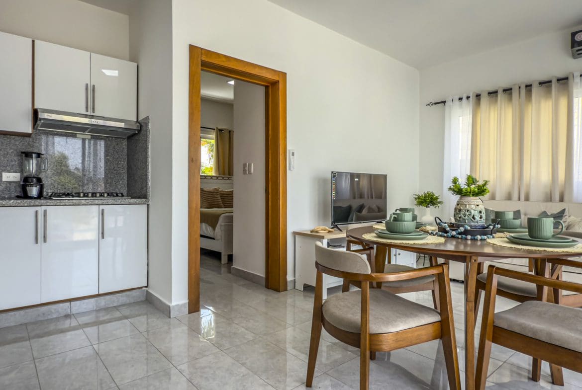 buyDRproperty Modern apartment interior with kitchen, dining area, living room, and bedroom visible through doorway. Sosua Real Estate