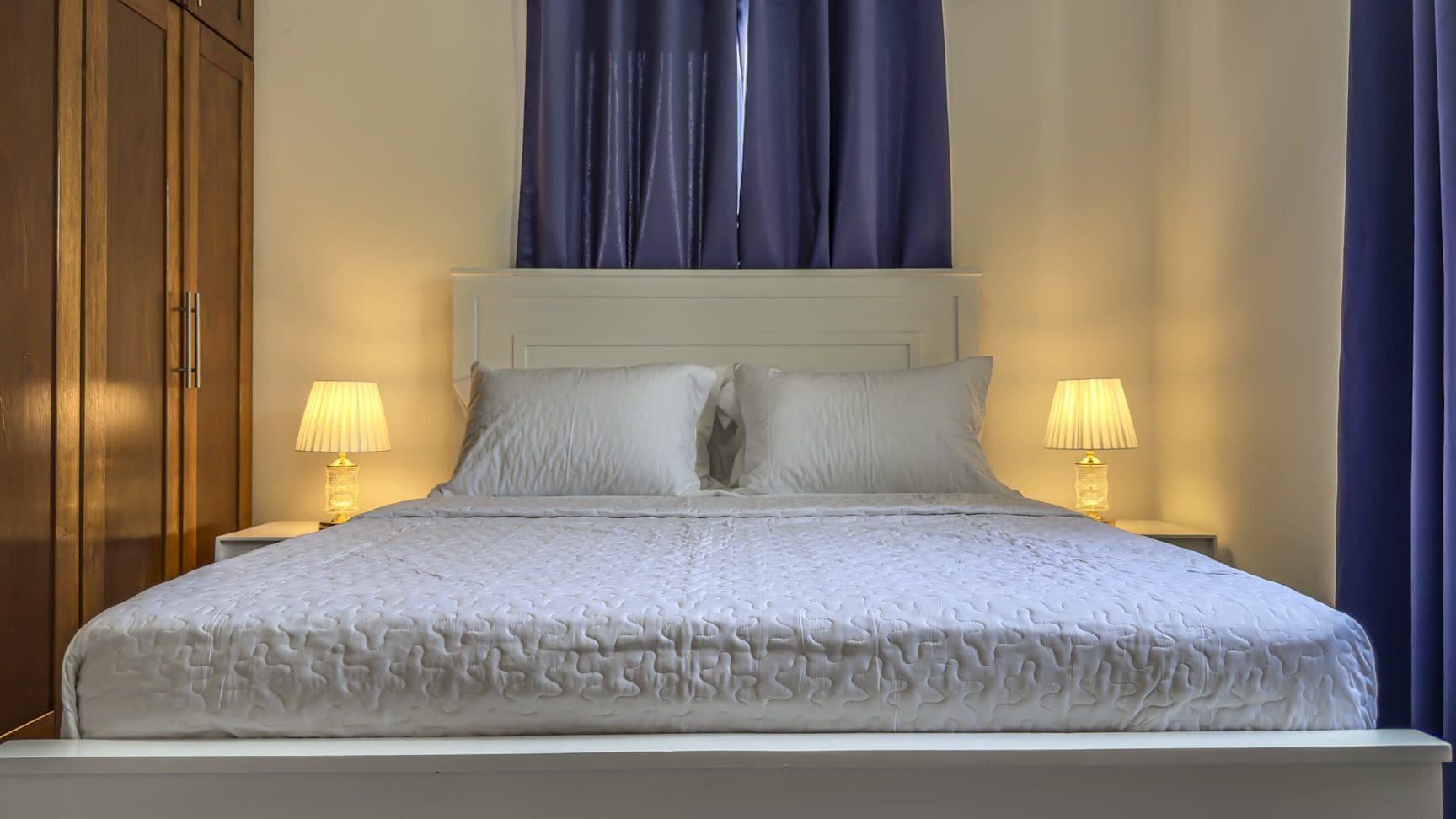 buyDRproperty Cozy small bedroom with white bed and warm lighting. Sosua Real Estate