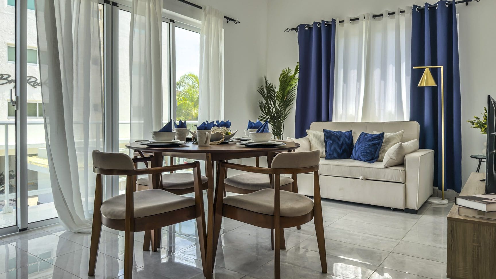 buyDRproperty Cozy dining area with round table, chairs, and sofa near window. Sosua Real Estate