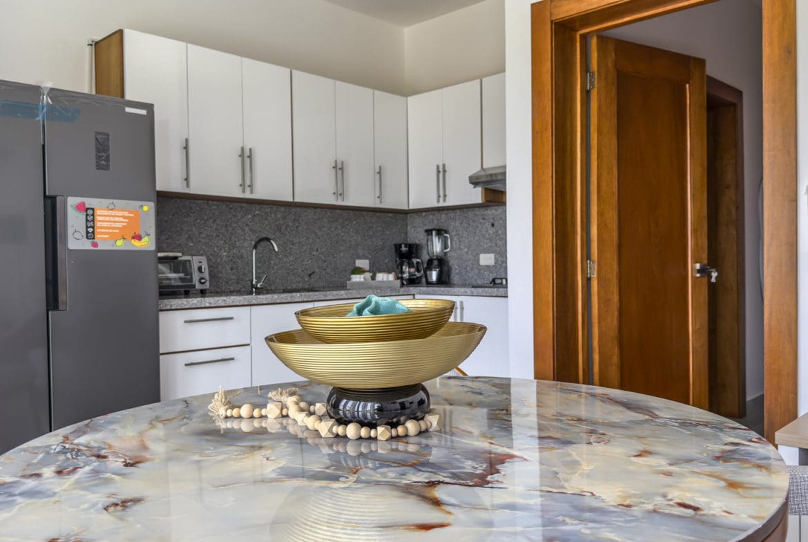 buyDRproperty Modern kitchen with marble table and decorative bowls. Sosua Real Estate