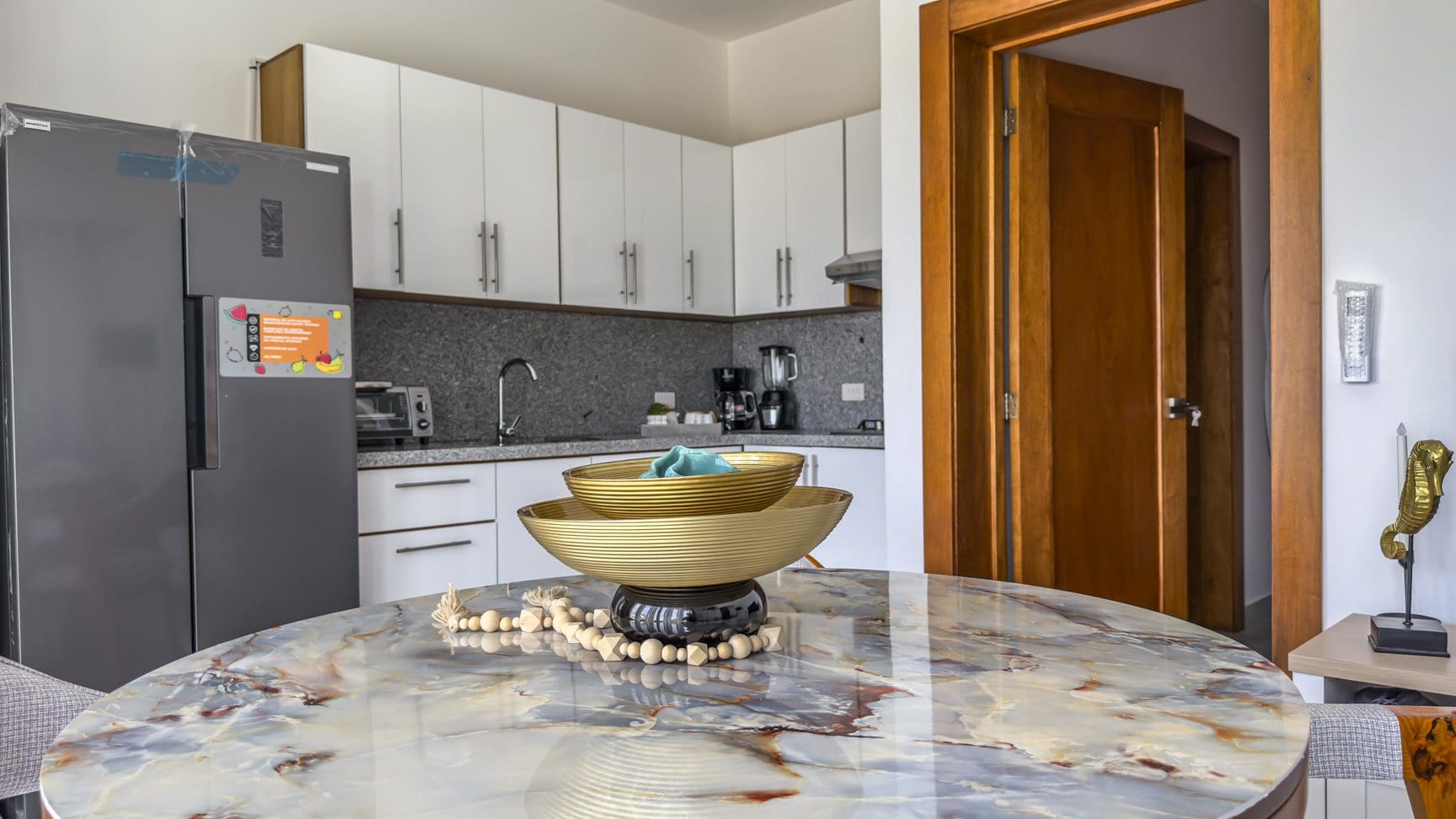 buyDRproperty Modern kitchen with marble table and decorative bowls. Sosua Real Estate